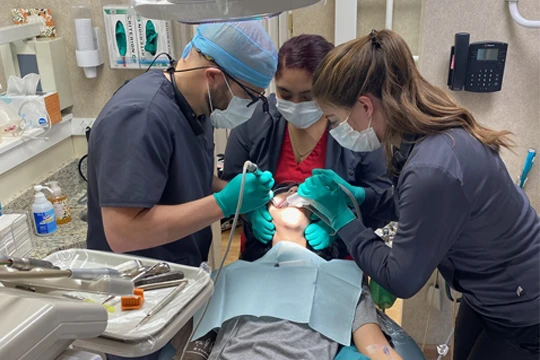 Dr. John Allen and two hygienists performing treatment on a patient who is laying in a dental exam chair